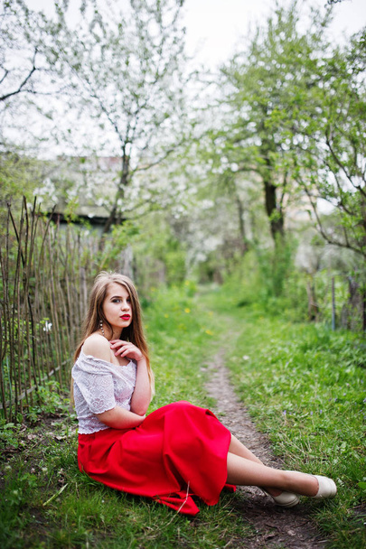 Portrait of sitting beautiful girl with red lips at spring bloss - Fotoğraf, Görsel