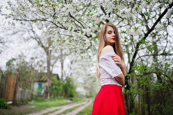 Portrait of beautiful girl with red lips at spring blossom garde - Photo, image