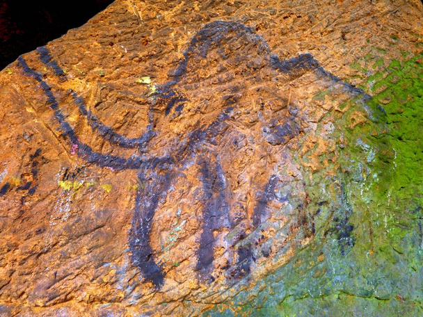 Arte prehistórico de mamut en cueva de arenisca. El foco brilla sobre la pintura histórica
 - Foto, Imagen