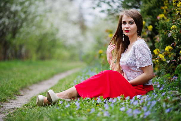 Portrait of sitiing beautiful girl with red lips at spring bloss - Photo, Image