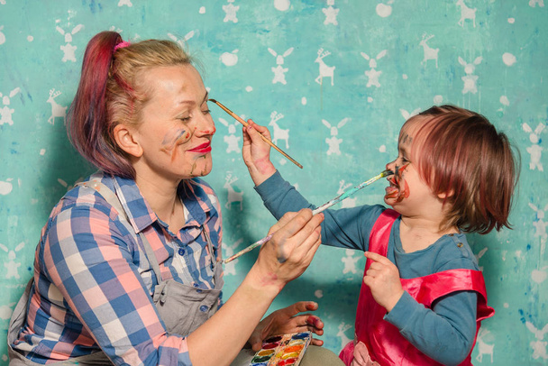 Mom and the child draw paints of each other's faces. - Valokuva, kuva