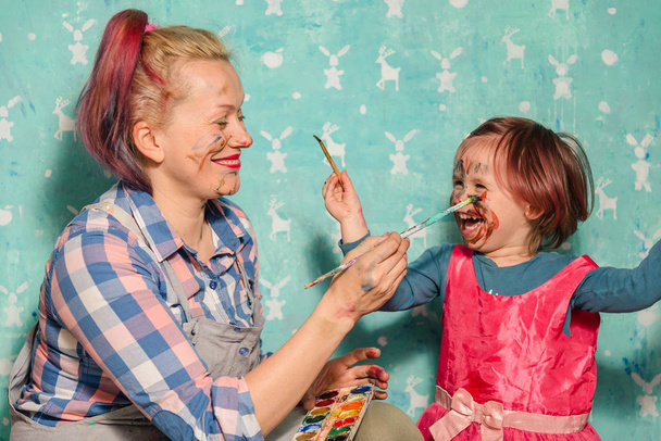 Mom and the child draw paints of each other's faces. - Photo, image