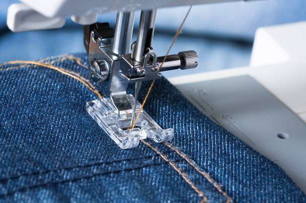 Foot Of Sewing Machine On Jeans Fabric. - 写真・画像