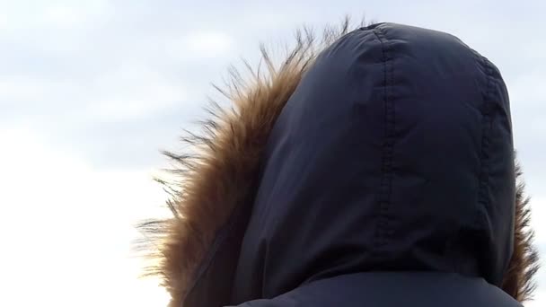 Мех на куртке движется по ветру на фоне светло-голубого неба в медленном движении
 - Кадры, видео