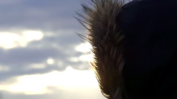 Pelz auf der Kapuze einer Jacke bewegt sich im Wind vor blauem Himmel in Zeitlupe - Filmmaterial, Video