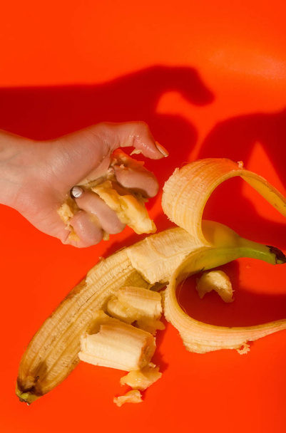 Female hand squeezing juice or squash from banana - Zdjęcie, obraz