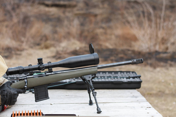 A man shoots a rifle. Rifle shooting with optical sight outdoors by man. - Photo, Image