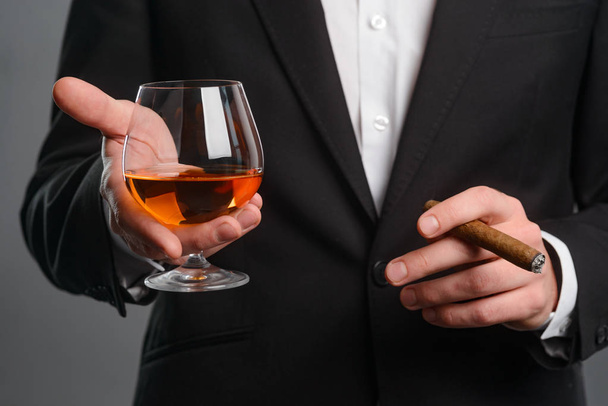 Cigar and glass in hands - Фото, зображення