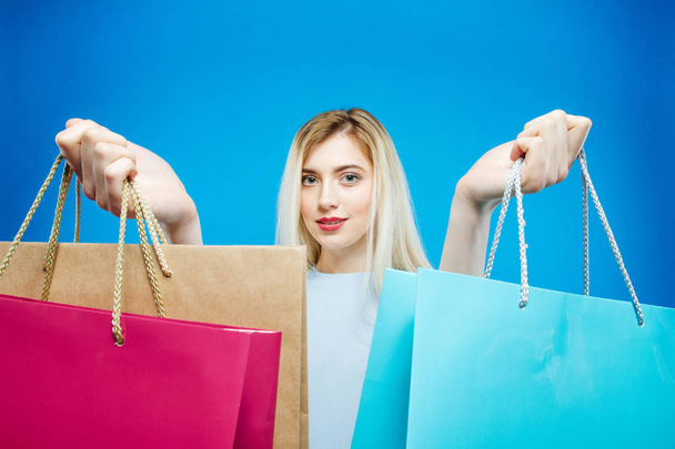 Blonde Female Shopper Wearing Dress is Holding Shopping Bags on Blue Background in Studio. - Foto, imagen