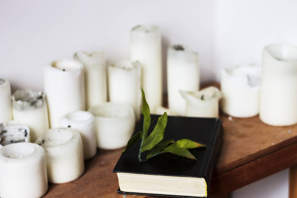  white candles and a black thick book - 写真・画像