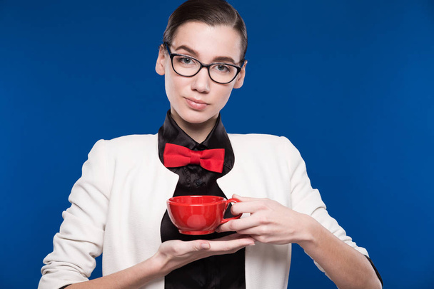 brunette in glasses with red cup in hands  - Foto, afbeelding