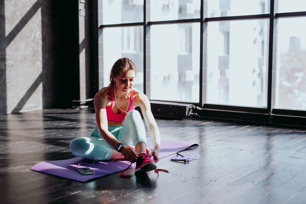 girl ties laces in gym - Foto, afbeelding