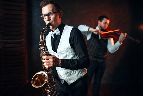 músicos do sexo masculino tocando saxofone e violino
 - Foto, Imagem