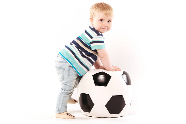 ребенок забирается на футбольный мяч
 - Фото, изображение