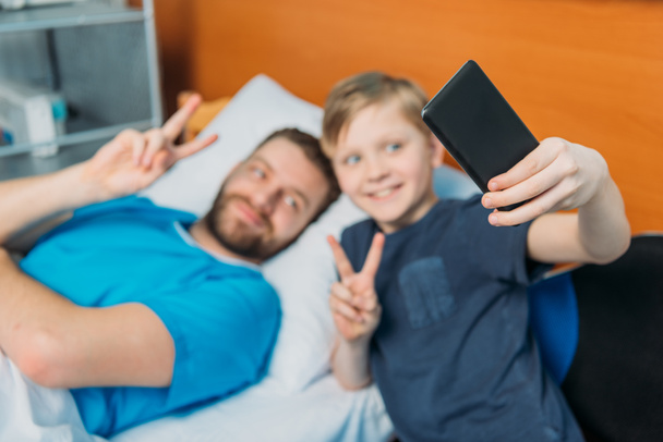 Ojciec i syn biorąc selfie w oddziale - Zdjęcie, obraz