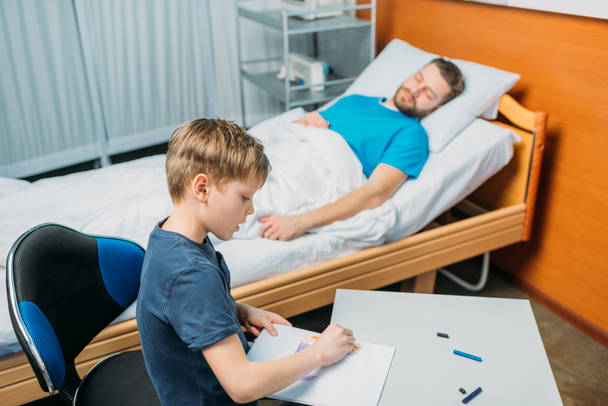 zoon tekenen terwijl zieke vader tot vaststelling van - Foto, afbeelding