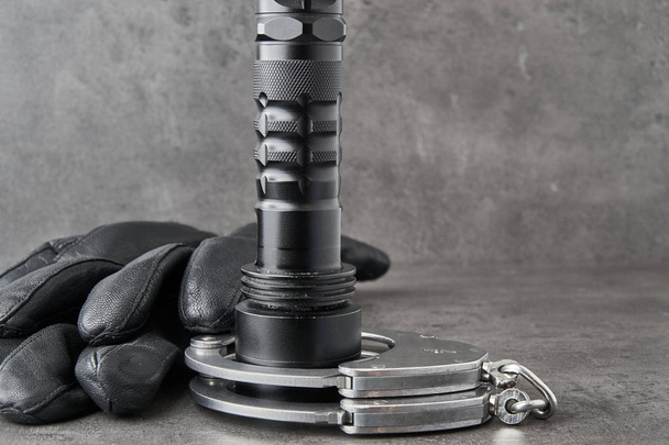 ドイツの警察手錠、革手袋、コピー領域を大まかな灰色の背景にたいまつ. - 写真・画像