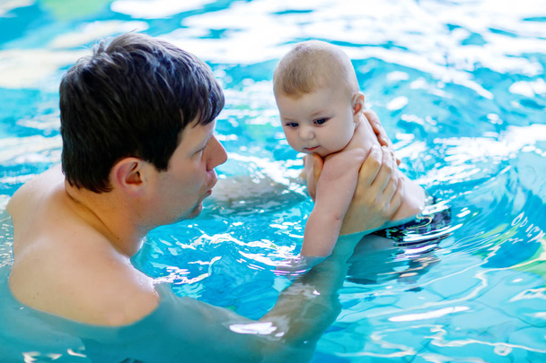 glücklicher Vater mittleren Alters schwimmt mit niedlichem, entzückendem Baby im Schwimmbad. - Foto, Bild