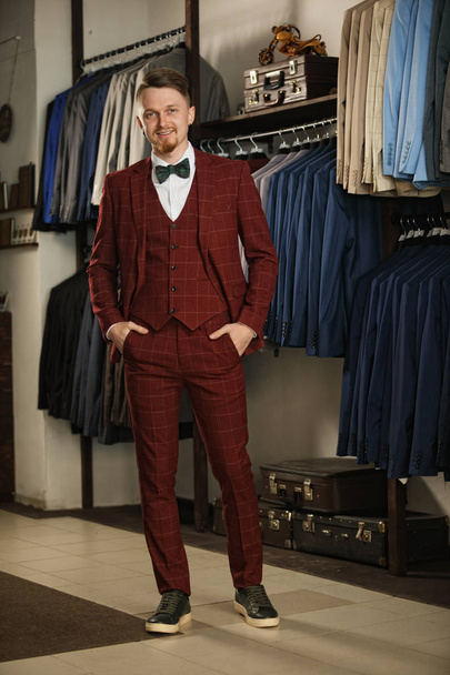 business, people, menswear, sale and clothes concept - happy young businessman over clothing store background - Foto, Bild