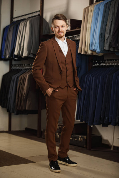 Handsome young man in classic suit. It is in the showroom, trying on clothes, posing. Advertising photo - Valokuva, kuva