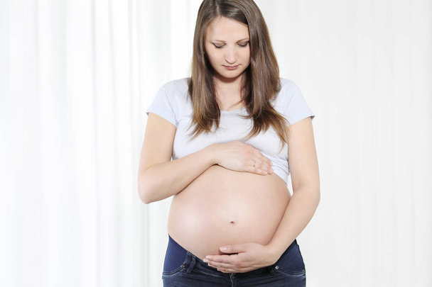 Young beautiful pregnant woman touching her belly with hands - Fotoğraf, Görsel