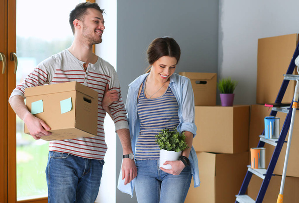 Happy young couple unpacking or packing boxes and moving into a new home - Foto, afbeelding