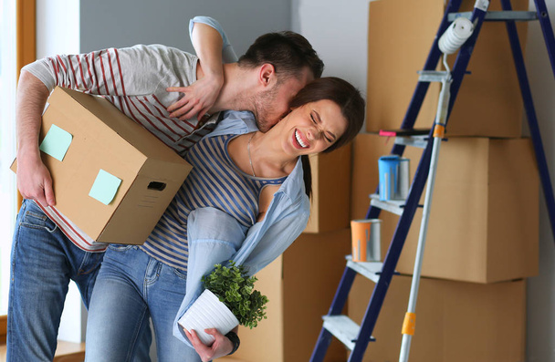 Happy young couple unpacking or packing boxes and moving into a new home - Zdjęcie, obraz