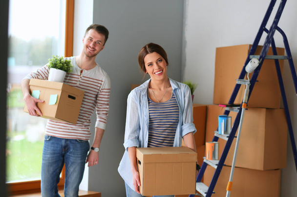 Happy young couple unpacking or packing boxes and moving into a new home - Zdjęcie, obraz