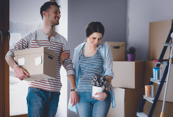 Happy young couple unpacking or packing boxes and moving into a new home - 写真・画像