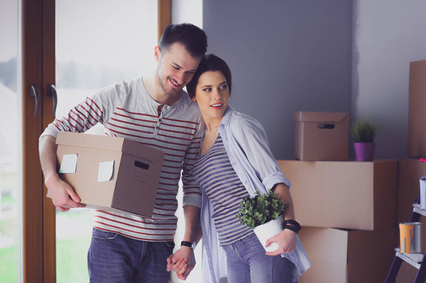 Happy young couple unpacking or packing boxes and moving into a new home - Фото, изображение