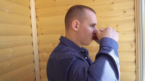 Un homme triste et déprimé buvant du thé près de la fenêtre à la maison - Séquence, vidéo