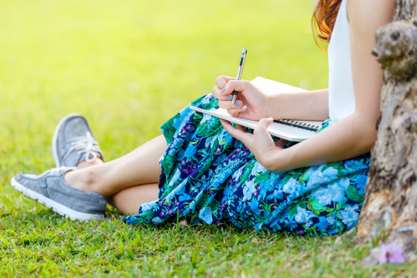 外の芝生の上のノートに書くペンで女性の手 - 写真・画像