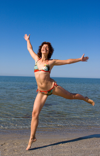 Счастливая улыбающаяся девушка прыгает на морском пляже
 - Фото, изображение