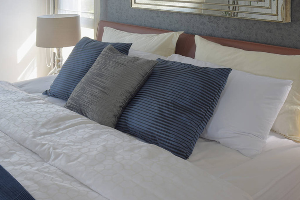 Gray and deep blue pillows on bed and white reading lamp in background - Foto, Imagem