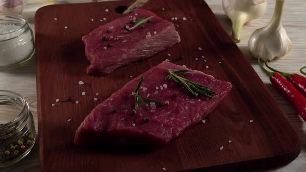 Beef fillet on a desk with pepper, rosemary and garlic. - Video, Çekim