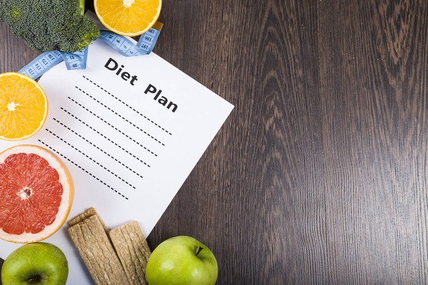 Food and sheet of paper with a diet plan on a dark wooden table. - 写真・画像