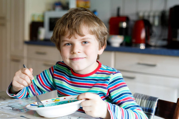 Adorable niño de la escuela comiendo sopa de verduras interior
. - Foto, imagen
