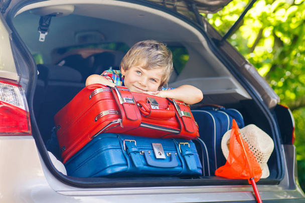 Little kid boy sitting in car trunk just before leaving for vaca - Foto, imagen