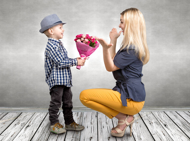Small son gives his beloved mother a beautiful bouquet of pink roses . Spring, concept of family vacation. Women's day,mother's day - Fotoğraf, Görsel