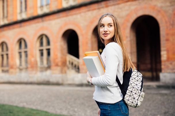 Smart Studentin mit Tasche und Büchern auf dem Campus im Freien - Foto, Bild