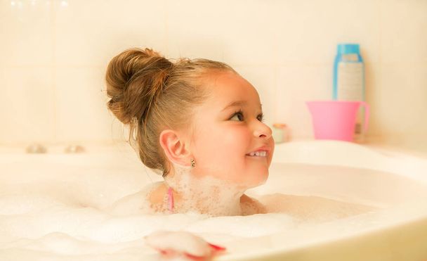 little beautiful girl playing with water and foam in bath - Photo, image