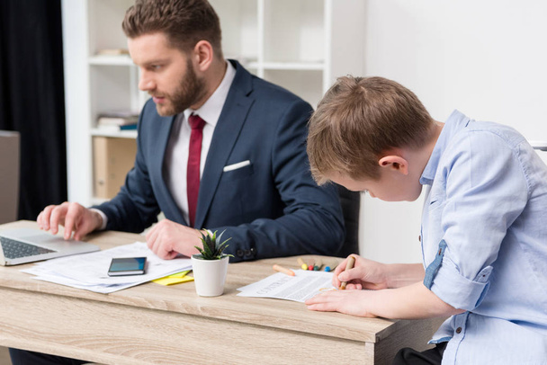 Businessman with son drawing on business papers - Photo, Image