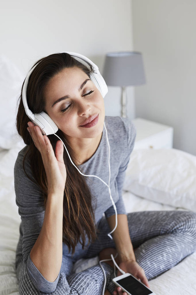 woman in pajamas listening to music - Фото, изображение