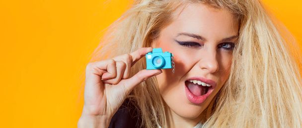 Beautiful girl portrait holding mini toy camera and winking, letterbox - Foto, Imagen