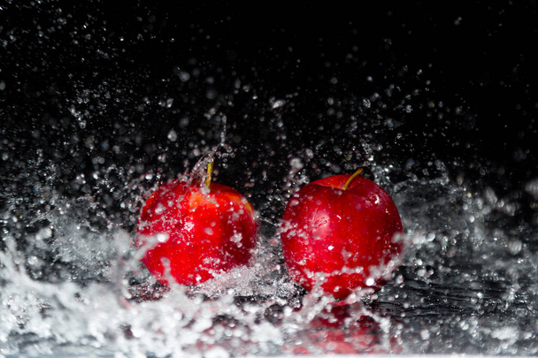Dos manzanas rojas en agua salpicada
 - Foto, Imagen