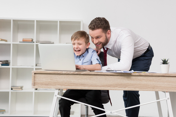 Empresario jugando en el ordenador portátil con hijo
 - Foto, imagen
