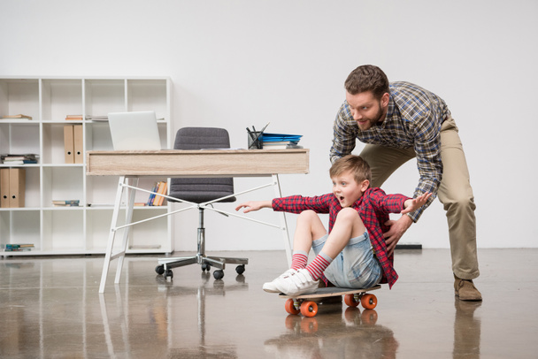 Homme d'affaires avec son fils sur skateboard
  - Photo, image