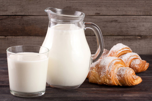 jug and glass of milk with croissants on a wooden background - Φωτογραφία, εικόνα