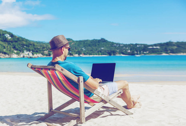 Young hipster man with laptop on tropical beach. Travel, vacatio - Foto, Imagem