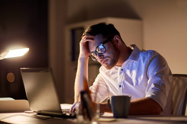 businessman with laptop thinking at night office - Zdjęcie, obraz
